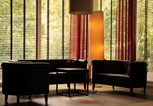 An image of a living room with floor to ceiling horizontal blinds.