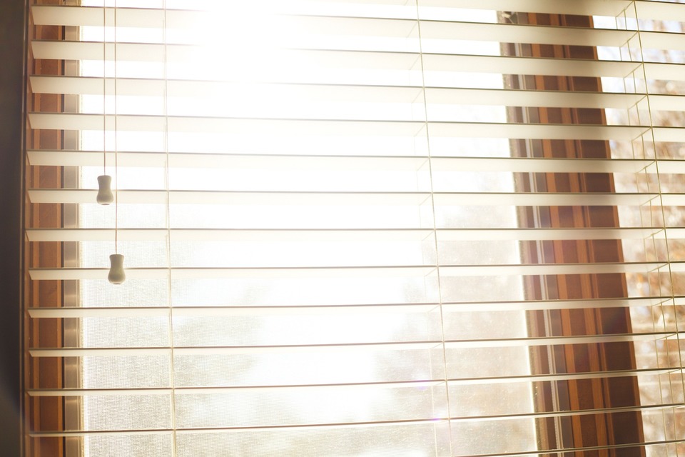 An image of a light wood coloured Venetian blind fixed at a window.