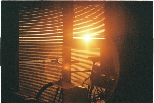 an image of a bike infront of a window where the sunlight is breaking through the shutter blind