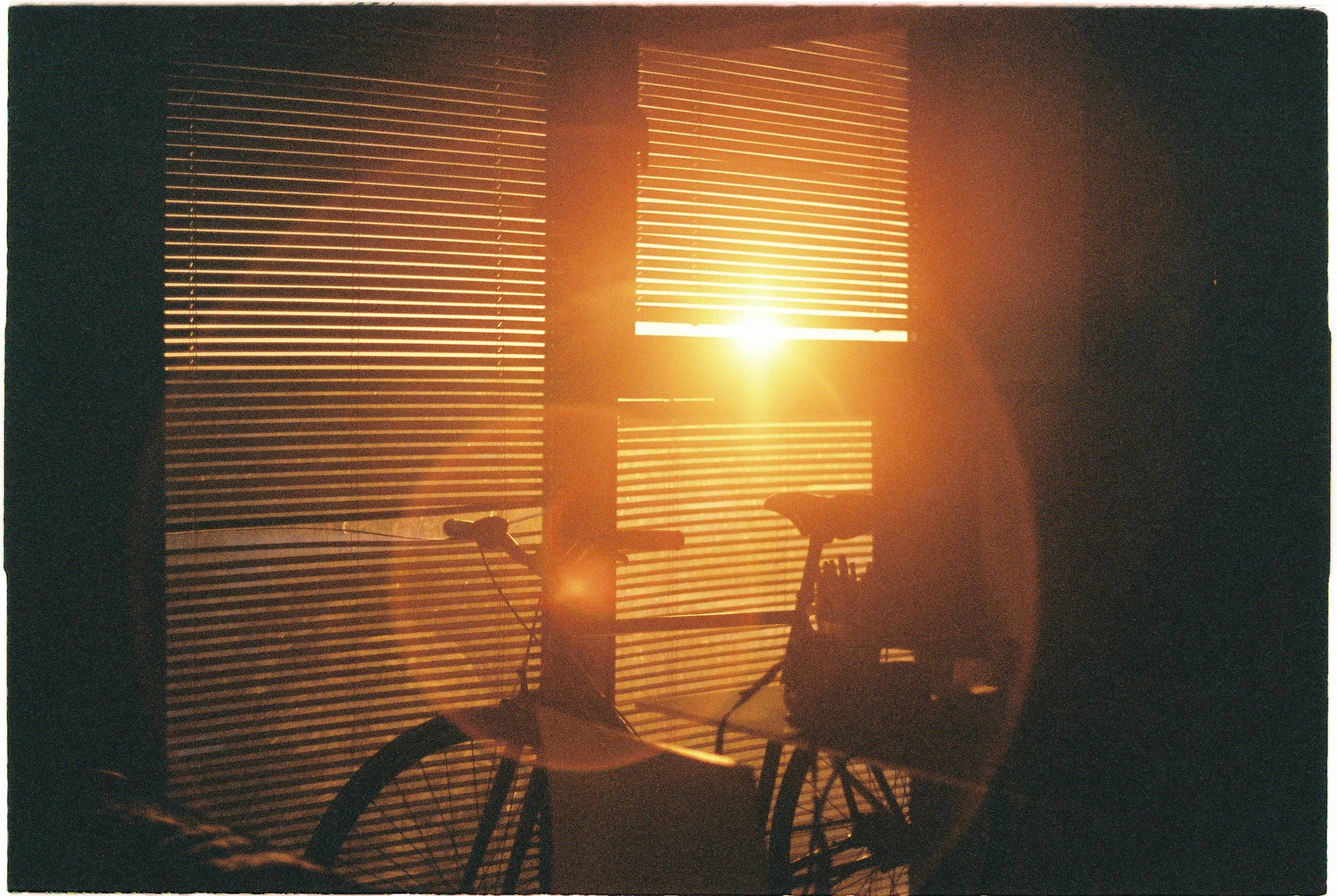 an image of a bike infront of a window where the sunlight is breaking through the shutter blind