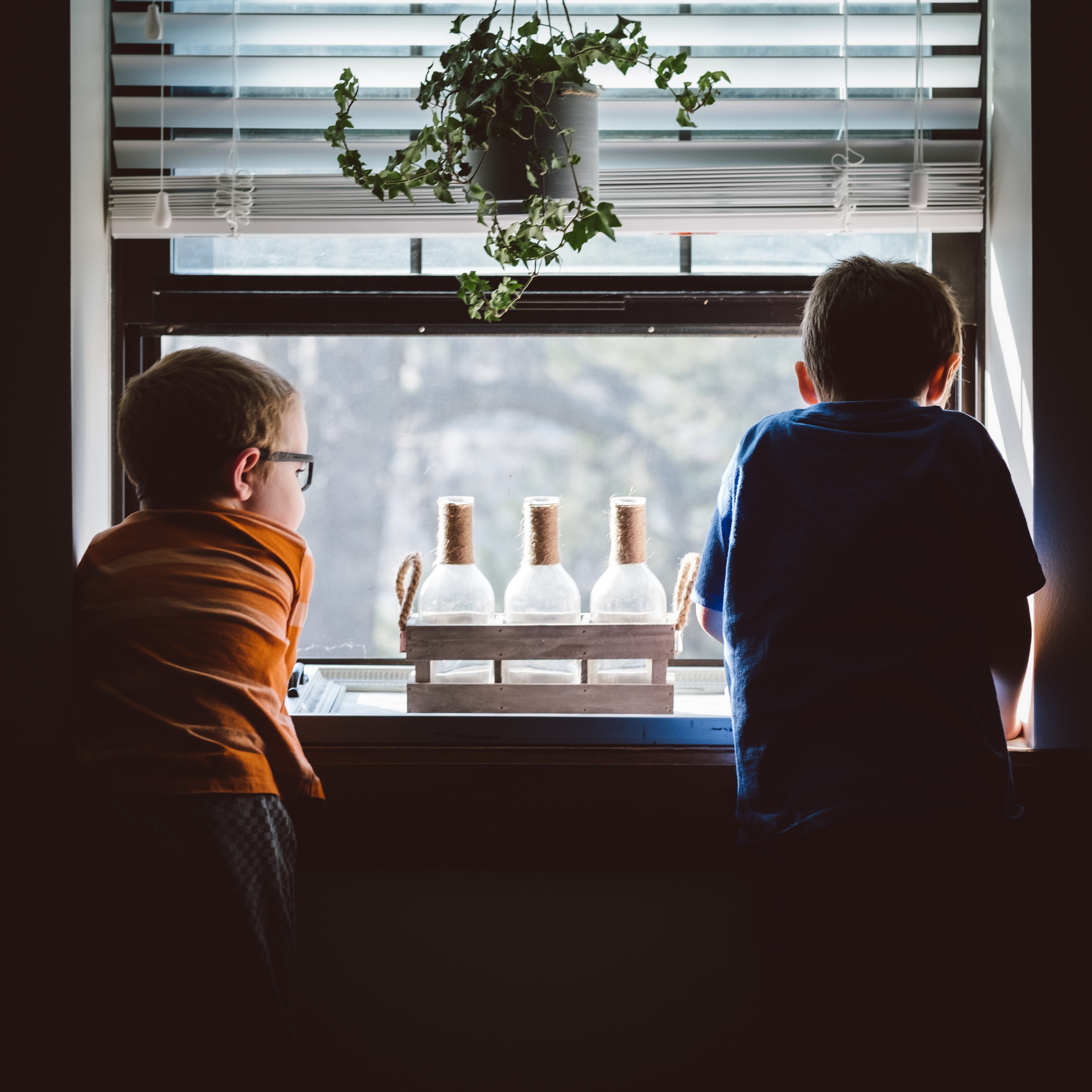 Two children sitting in front of a window